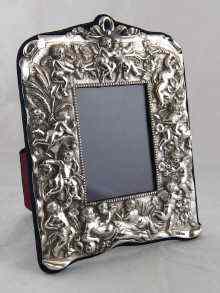 Appraisal: A heavily embossed silver strut back photo frame with amorini