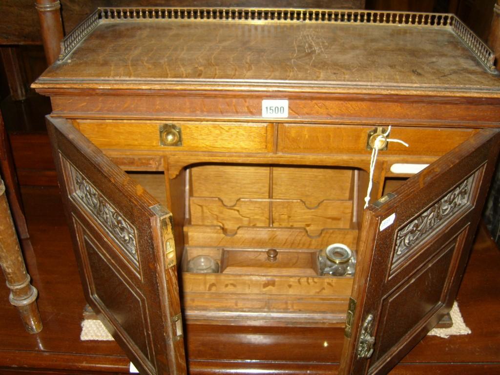 Appraisal: A small Victorian oak writing cabinet enclosed by two carved