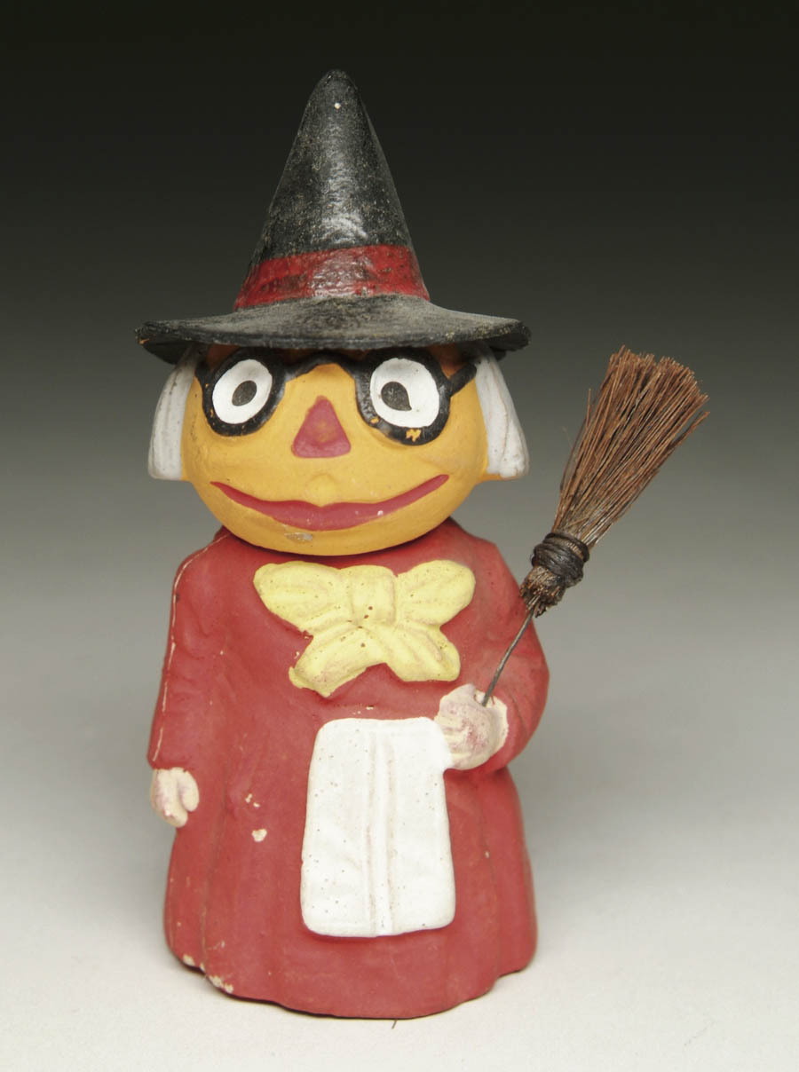 Appraisal: PUMPKIN-HEAD WITCH FIGURAL CANDY CONTAINER All composition red-dressed witch holding