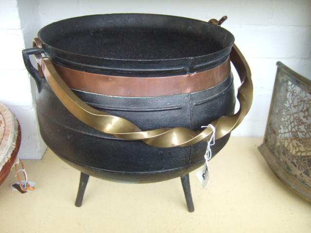 Appraisal: A cast iron cauldron with brass swing over handle