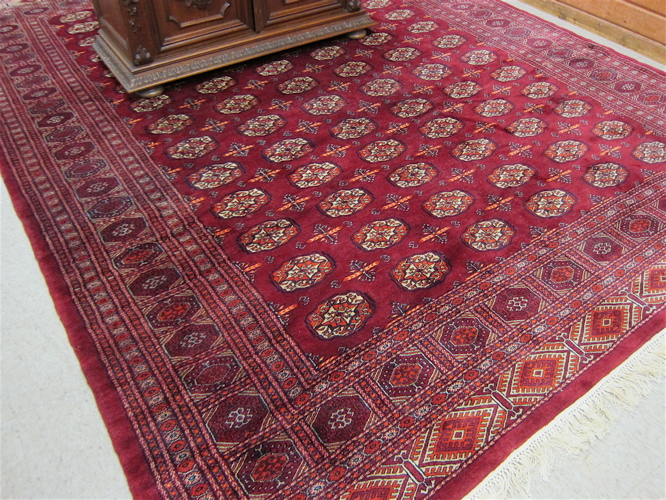 Appraisal: RED FIELD BOKHARA CARPET Pakistani made traditional Turkoman gol design