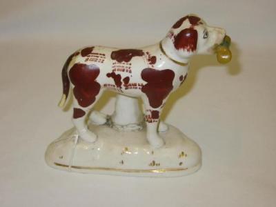 Appraisal: A STAFFORDSHIRE POTTERY FIGURE modelled as a standing dog holding