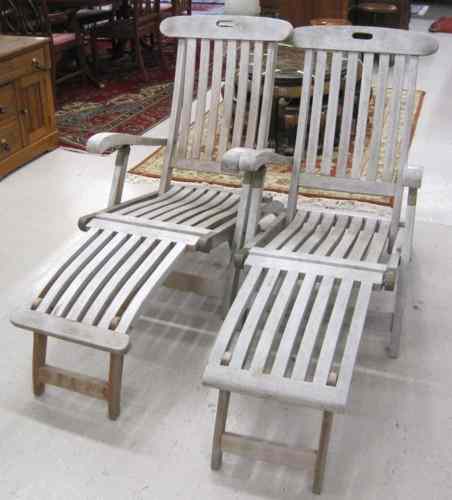 Appraisal: PAIR OF FOLDING LOUNGE DECK CHAIRS of weathered teak construction