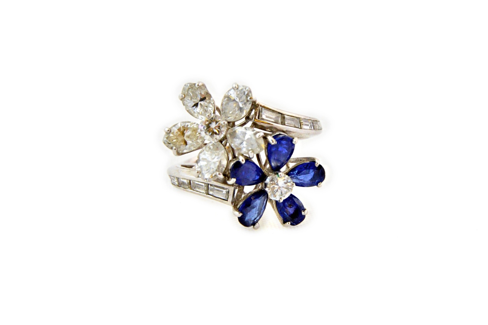 Appraisal: A sapphire and diamond twin flowerhead crossover ring in the