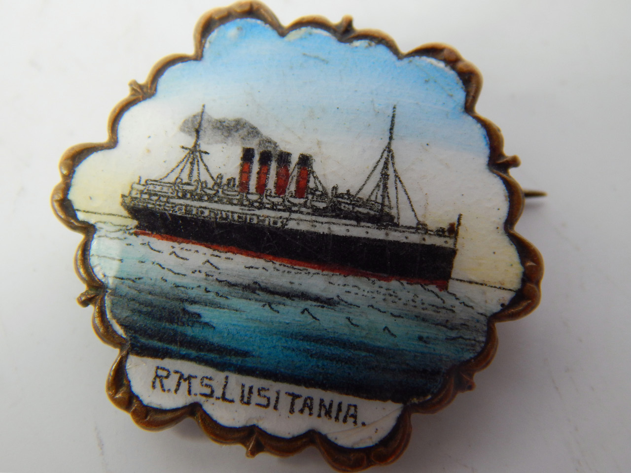 Appraisal: A brass and enamel souvenir badge for the RMS Lusitania