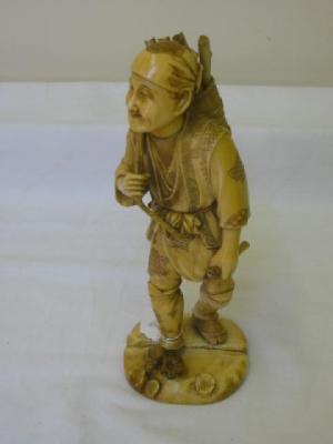 Appraisal: A JAPANESE IVORY OKIMONO modelled as a wood cutter wearing