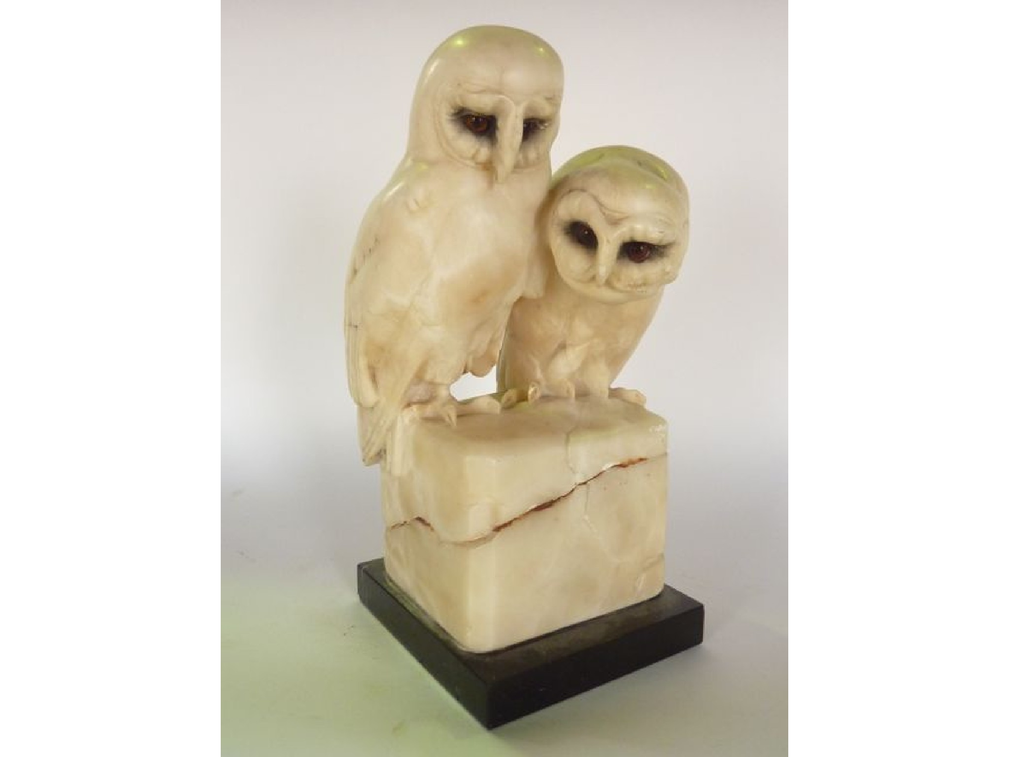 Appraisal: A white alabaster study of two owls perching upon a