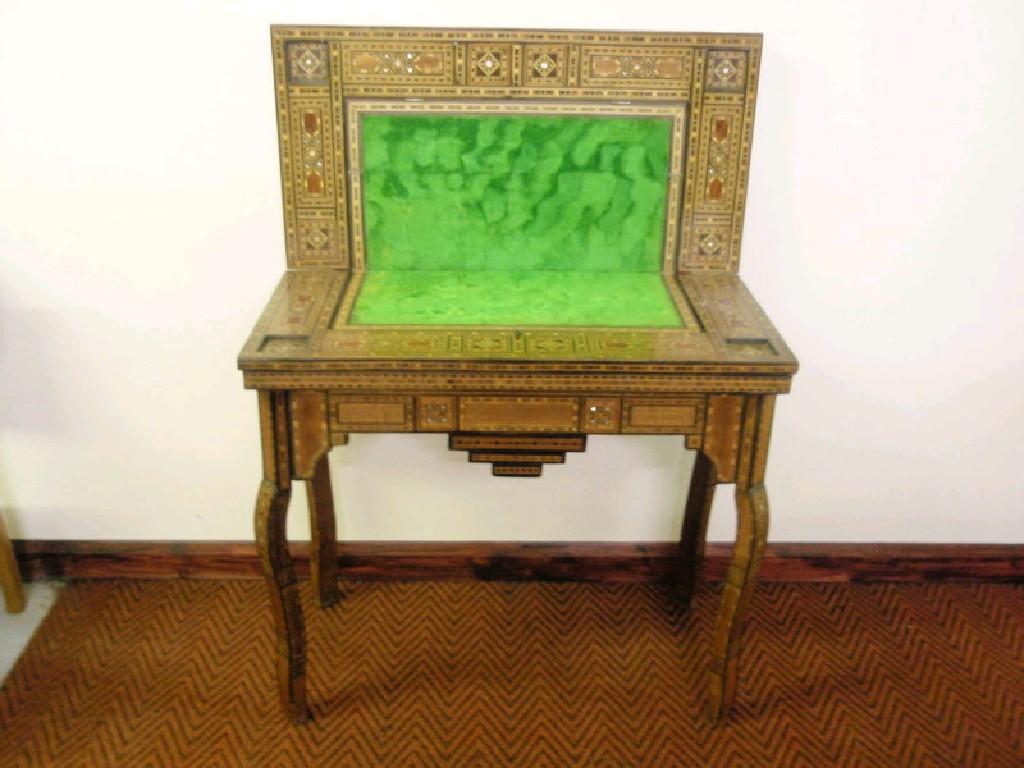 Appraisal: A marquetry inlaid fold-over games table with inset counter wells