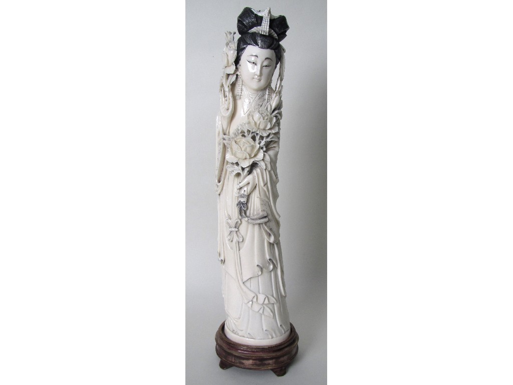 Appraisal: A Chinese carved ivory tusk figure of Guanyin holding posies