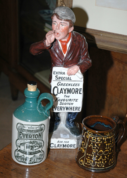 Appraisal: A CLAYMORE SCOTCH ADVERTISING FIGURE Together with a stoneware mug