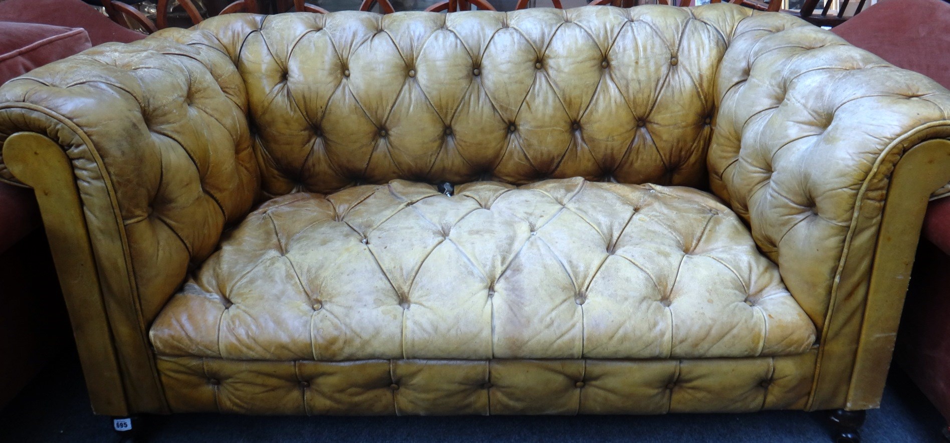 Appraisal: A small button leather upholstered Chesterfield sofa on stained beech