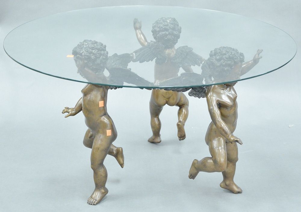 Appraisal: Round Glass Top Coffee Table having triple bronze cherub base