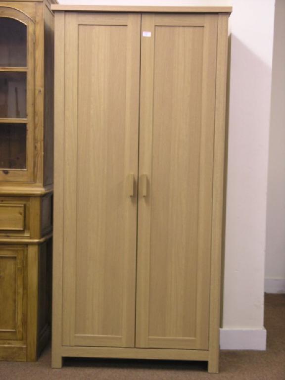 Appraisal: A modern oak finished single wardrobe enclosed by a pair