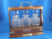 Appraisal: An oak tantalus with three cut glass decanters and locking