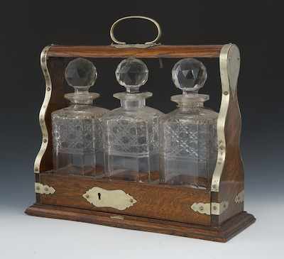 Appraisal: An Antique Oak Tantalus Three cut glass decanters with stoppers