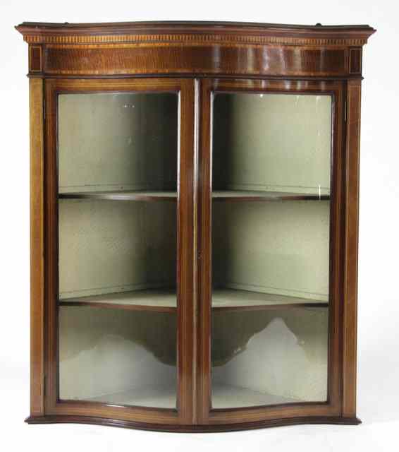 Appraisal: An Edwardian mahogany serpentine hanging corner cupboard circa with glass