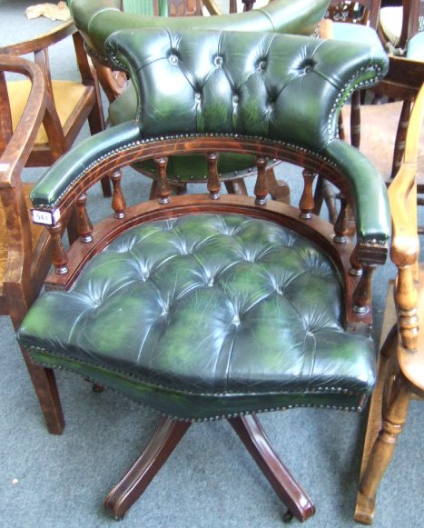 Appraisal: A stained beech and leather captains chair with scroll-over back