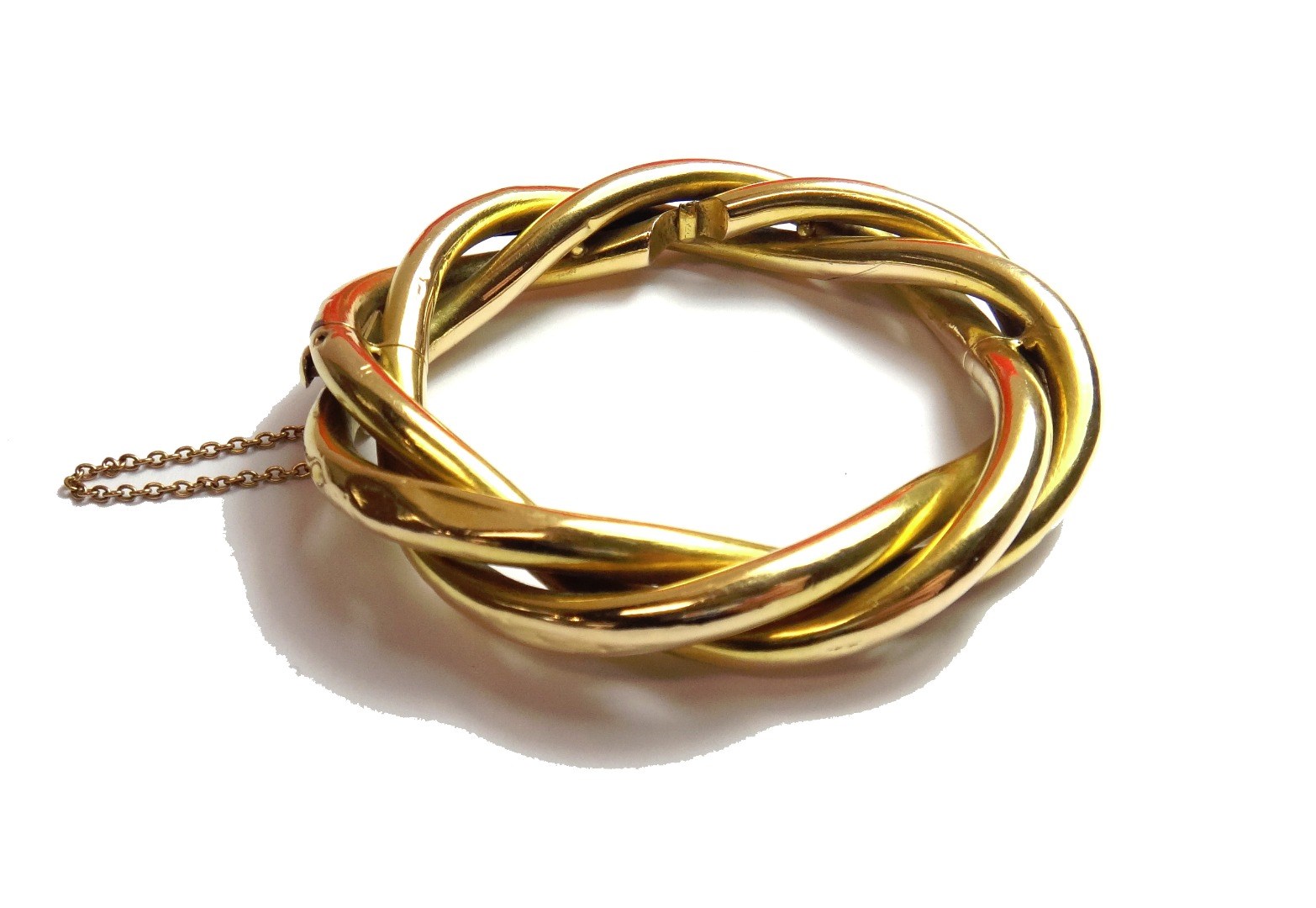 Appraisal: A gold oval hinged bangle in a three row interwoven