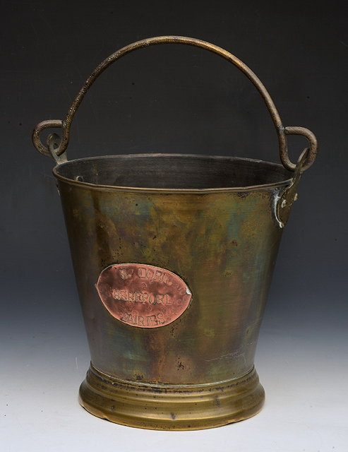 Appraisal: A BRASS BUCKET with overhead iron handle and copper plaque