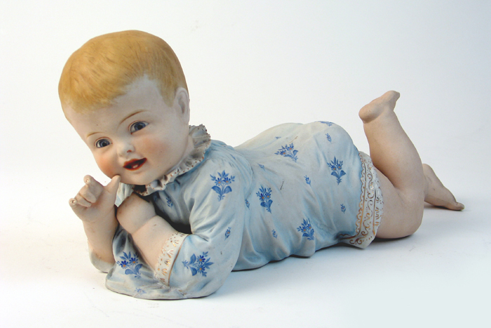 Appraisal: A PORCELAIN BISQUE PIANO BABY in a recumbent position hand