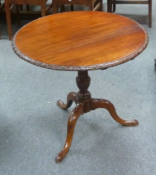 Appraisal: A circular mahogany table with carved border on a fluted