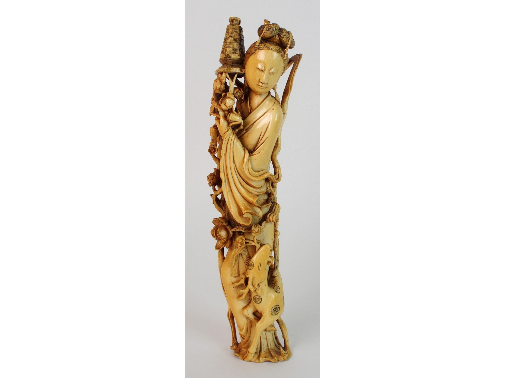 Appraisal: A Chinese ivory okimono of Guanyinstanding with a deer at