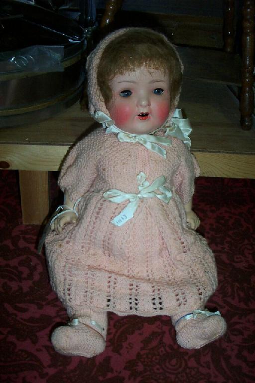 Appraisal: A composition headed doll dressed in a pink knitted costume