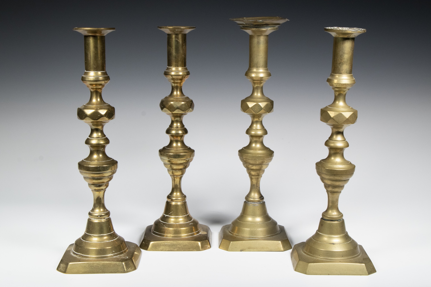 Appraisal: BRASS PUSH-UP CANDLESTICKS Group of English Brass Candlesticks with turned