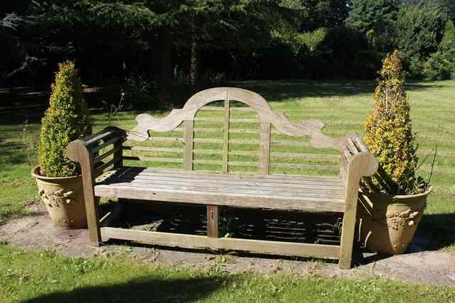 Appraisal: A TEAK LUTYENS STYLE GARDEN SEAT with camel back and