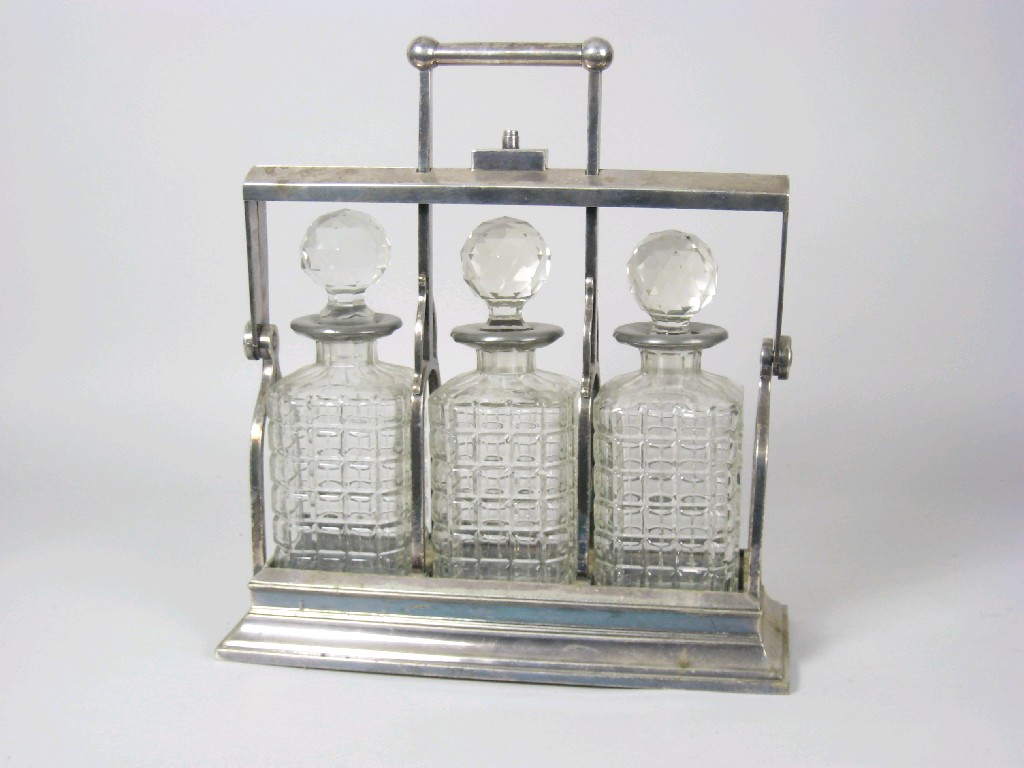 Appraisal: A silver plated three bottle Tantalus in the style of