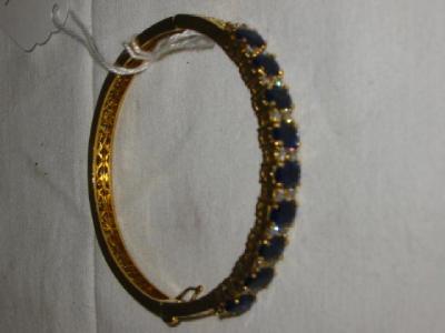 Appraisal: AN CT GOLD BANGLE set with nine blue sapphires each