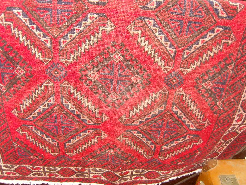 Appraisal: A red ground eastern wool rug with repeating geometric and