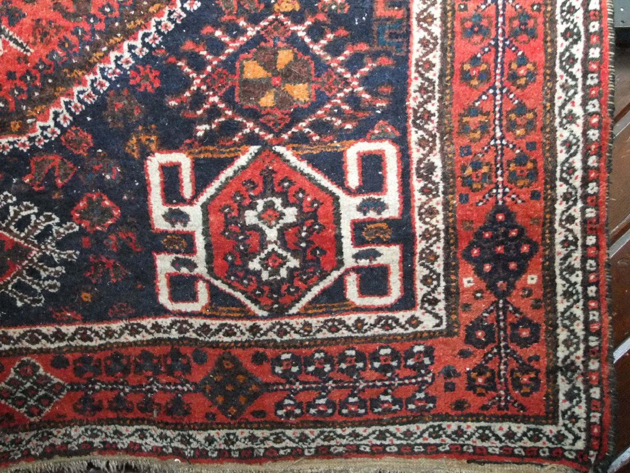 Appraisal: A coarse wool eastern carpet with mid-red field within a