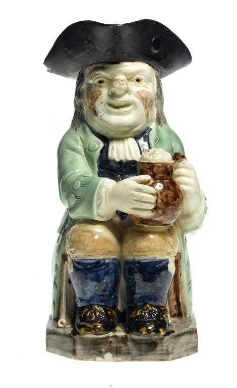 Appraisal: A WOOD-TYPE CREAMWARE TOBY JUG the seated toper holding a