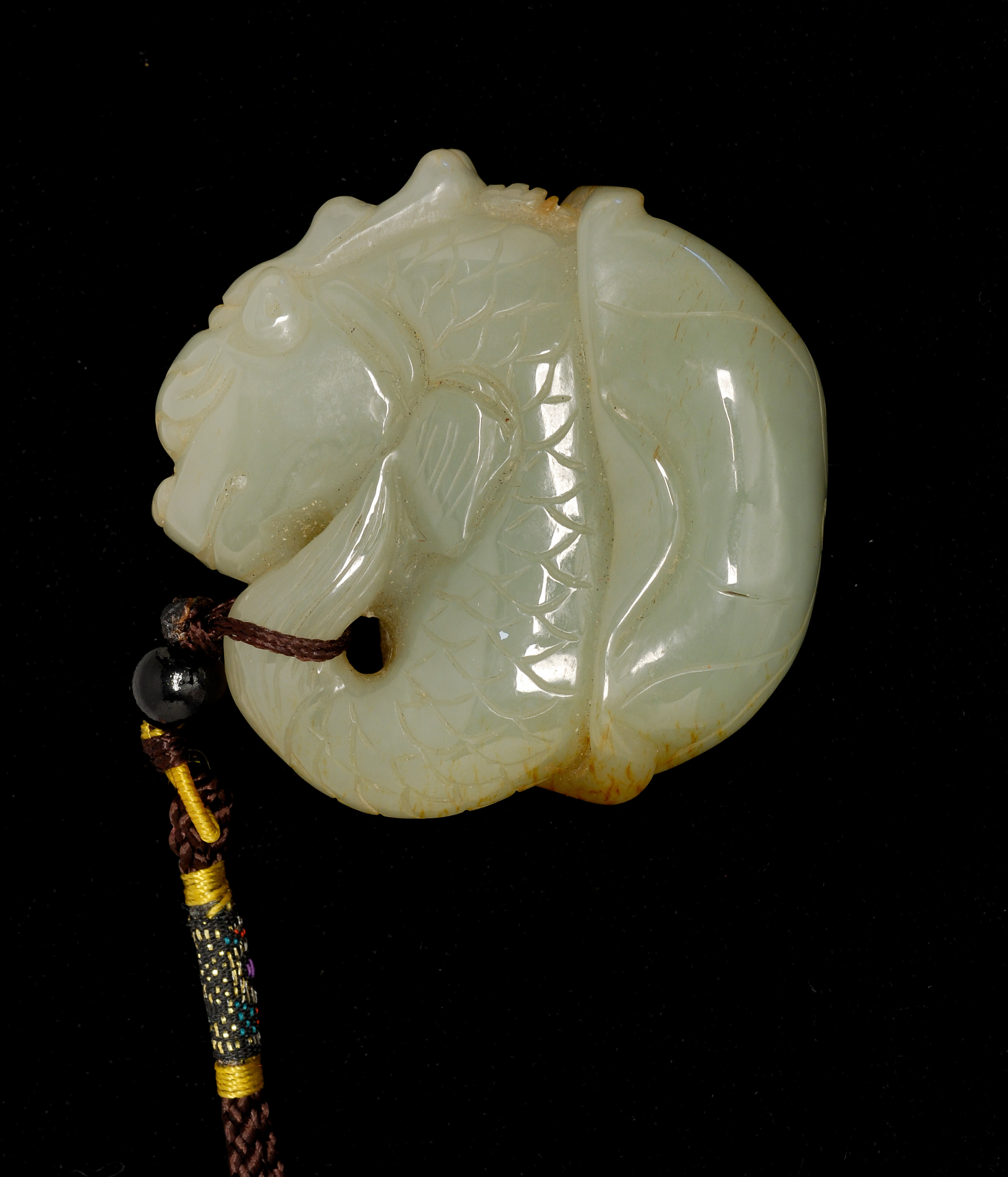 Appraisal: CELADON AND RUSSET JADE PENDANT In fishdragon and lotus form