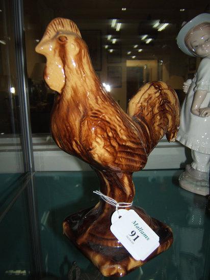 Appraisal: A th Century honey glazed pottery cockerel standing on a