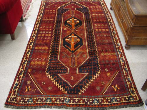 Appraisal: PERSIAN SHIRAZ CARPET centering twin geometric medallions on red ground