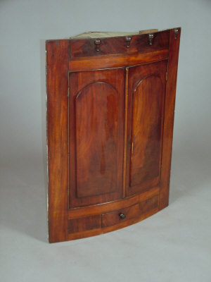 Appraisal: A mahogany bowfront hanging corner cabinet early th century with