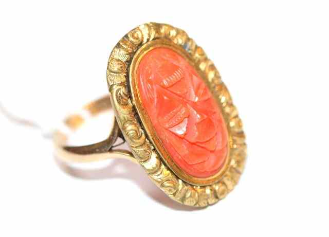 Appraisal: A CORAL SET DRESS RING oval carved coral panel set