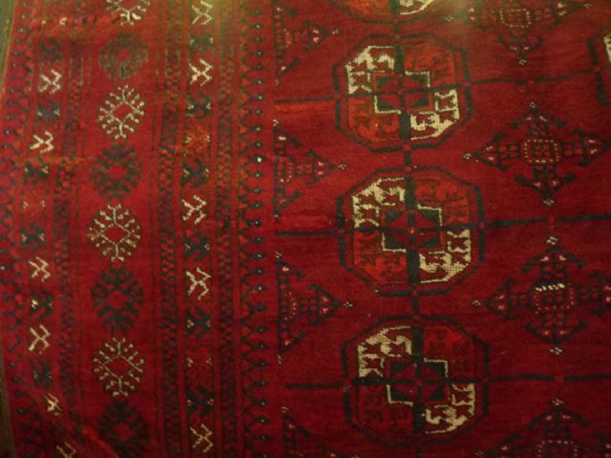 Appraisal: An Afghan red ground wool carpet with multi-medallion detail in