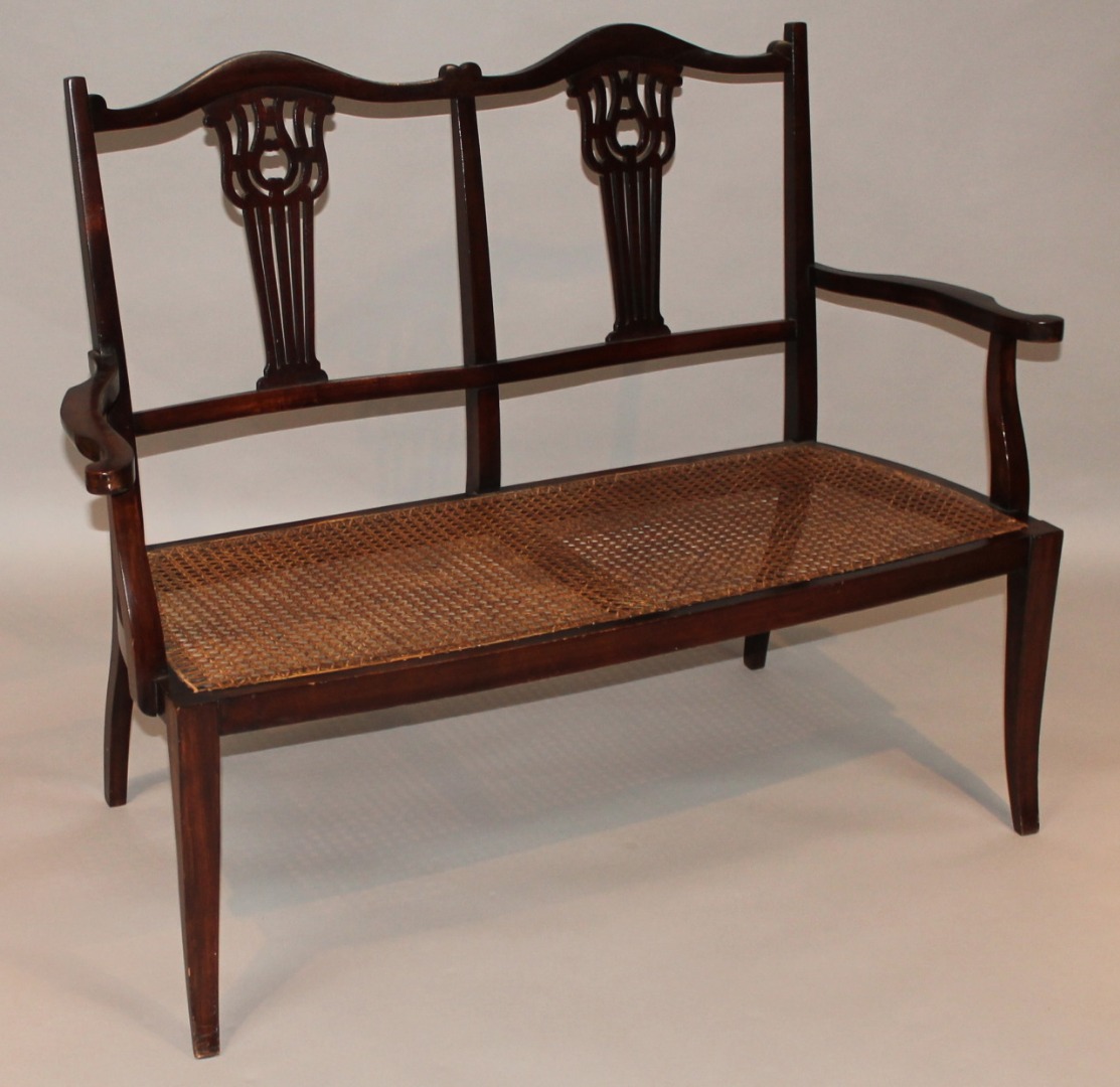 Appraisal: An Edwardian mahogany double backed settee with pierced scroll splats