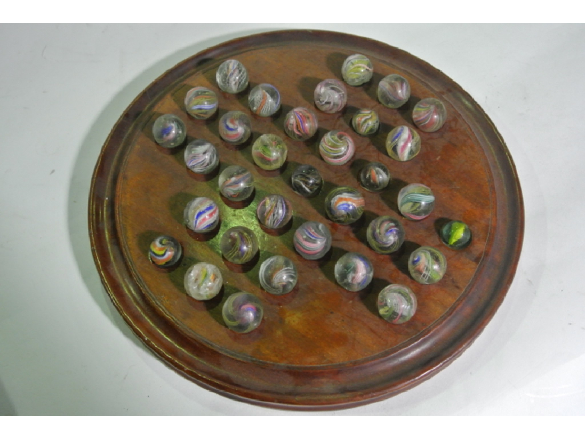 Appraisal: A mahogany solitaire board populated with antique Latticino glass marbles