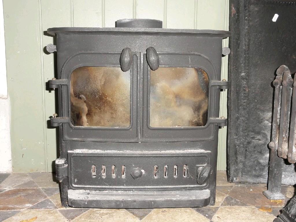 Appraisal: A small but heavy cast iron wood burning stove enclosed