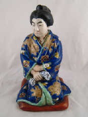 Appraisal: A ceramic kneeling Japanese figure in brightly coloured well detailed