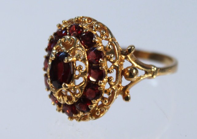 Appraisal: A garnet oval cluster ring on an open work setting