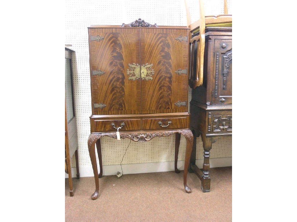 Appraisal: A mahogany cocktail cabinet pair of flame-veneered doors enclosing plate