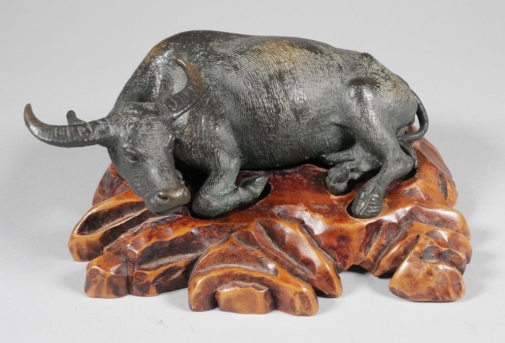 Appraisal: Patinated bronze water buffalo lying on custom carved wooden stand