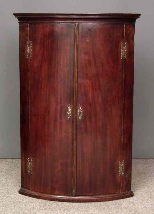 Appraisal: A George III mahogany bow-front hanging corner cupboard the green