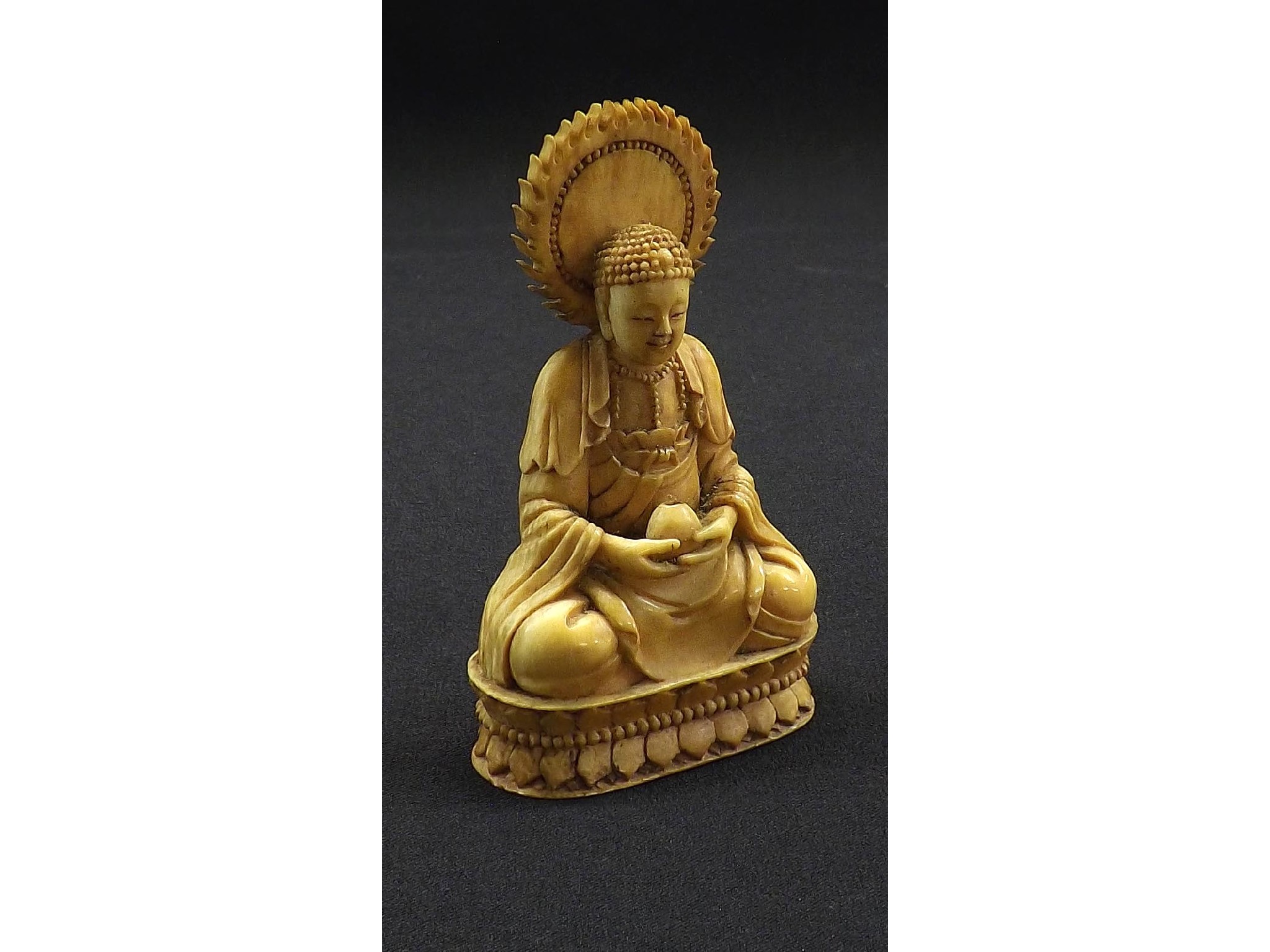 Appraisal: Carved and stained ivory figure modelled as a deity seated