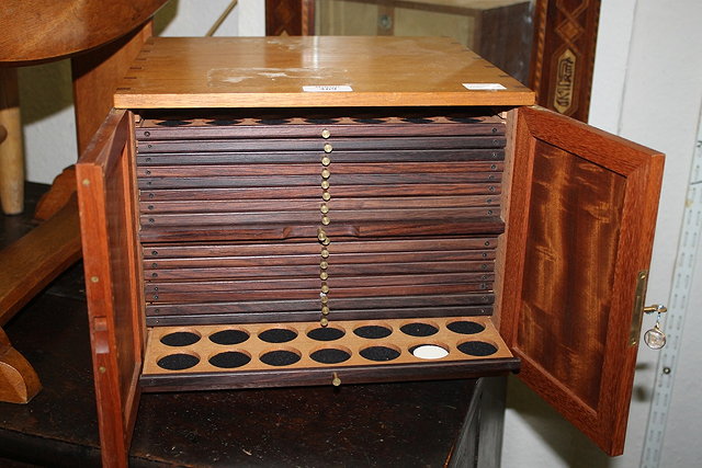 Appraisal: A HARDWOOD COIN CABINET enclosed by two panel doors and